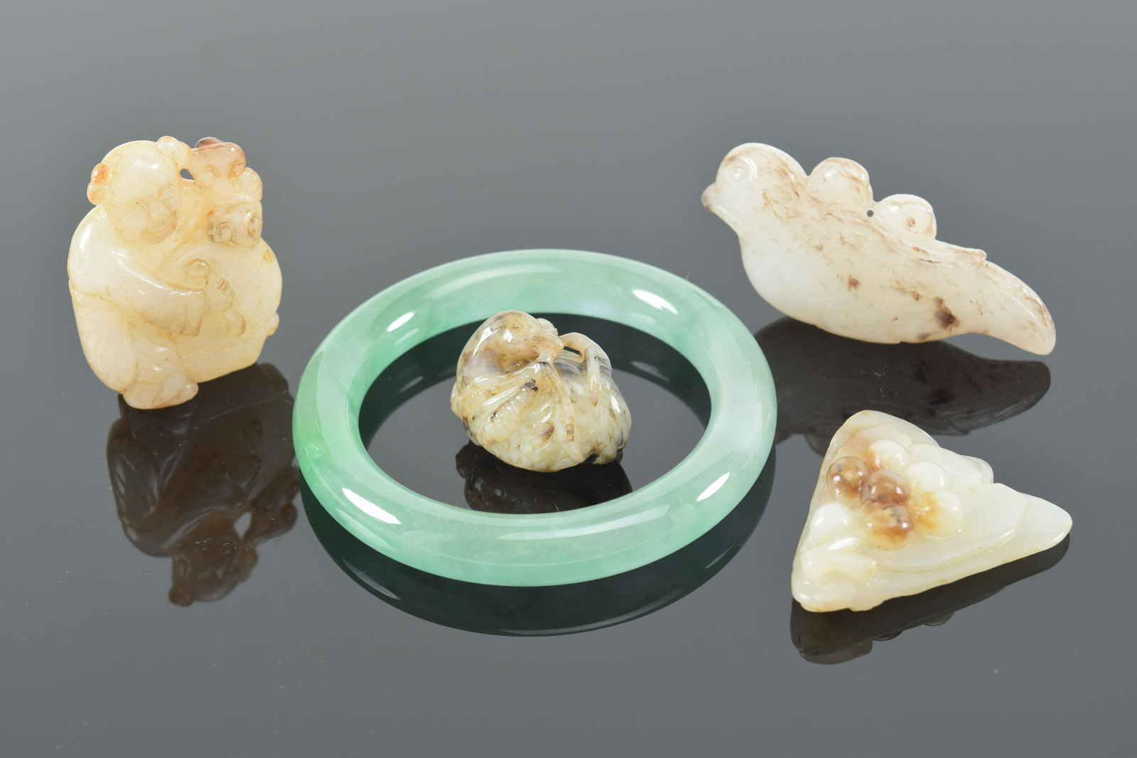 Lot of 5 jade carvings. China. 19th/20th century. To include a jadeite bracelet and 4 pendants. (1 of 6)