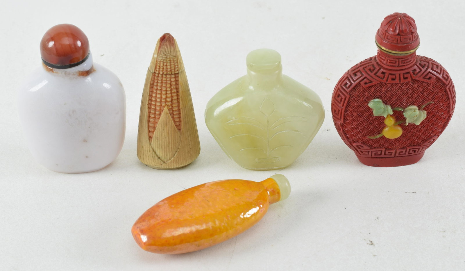 5 snuff bottles. China. Late 19th/early 20th century. To include: hardstone inlaid cinnabar snuff: 5 snuff bottles. China. Late 19th/early 20th century. To include: hardstone inlaid cinnabar snuff bottle, yellow porcelain snuff bottle, the others of agate and soapstone. Largest 3in.