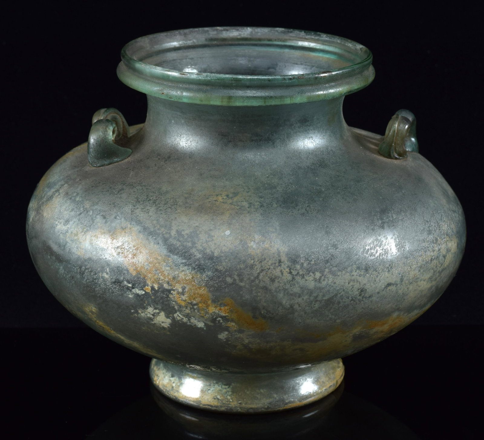 Large ancient Roman glass handled vase. Footed base with a wide body and pinched neck. Applied: Large ancient Roman glass handled vase. Footed base with a wide body and pinched neck. Applied scrolled handles. Loss to foot. Light teal color. 7.5in diameter.