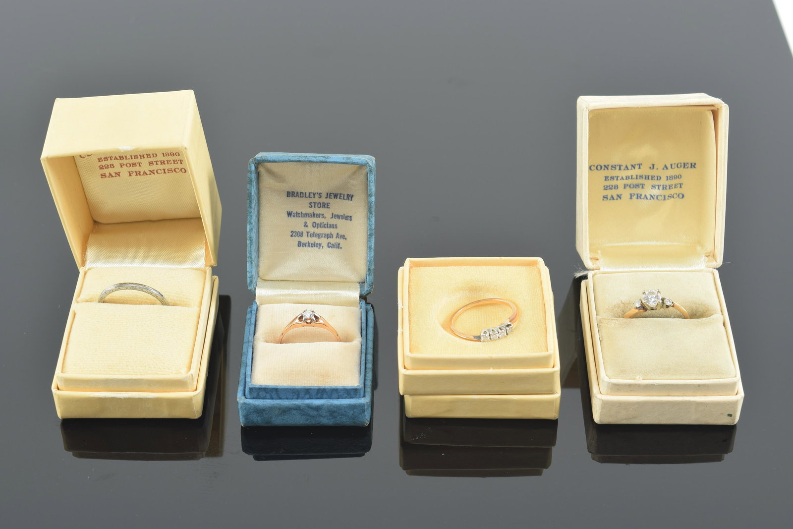 4 gold rings - 3 diamond mounted. 1) 3 stone diamond ring. Center stone .39mm diameter. Unmarked. 2): 4 gold rings - 3 diamond mounted. 1) 3 stone diamond ring. Center stone .39mm diameter. Unmarked. 2) Small solitaire diamond ring marked 14K. 3) 4 stone ring. Faded mark. 4) 18K marked white gold band