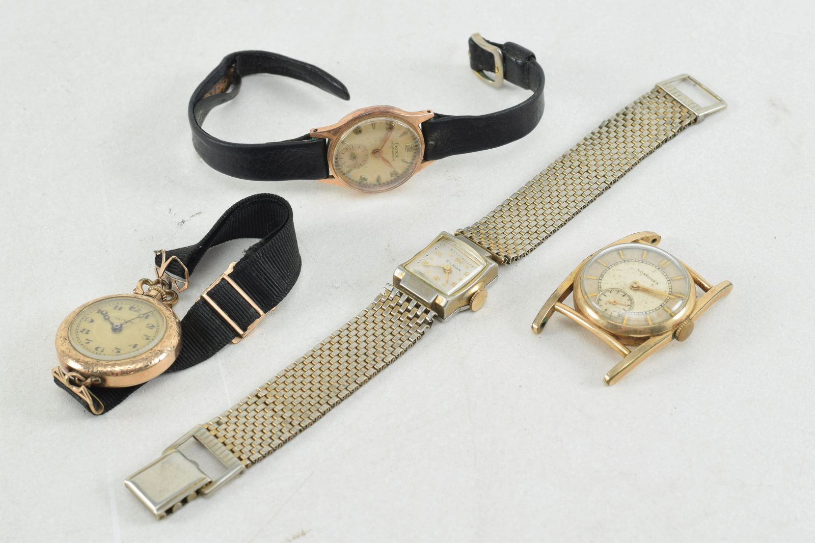4 vintage wristwatches. 1) Longines gold filled. No band. 2) Doxa - Anti Magnetique. Serial #: 4 vintage wristwatches. 1) Longines gold filled. No band. 2) Doxa - Anti Magnetique. Serial # 912877. Black band. 3) Trinite Swiss watch. Black band. 4) Elbon Swiss watch. Metal band.