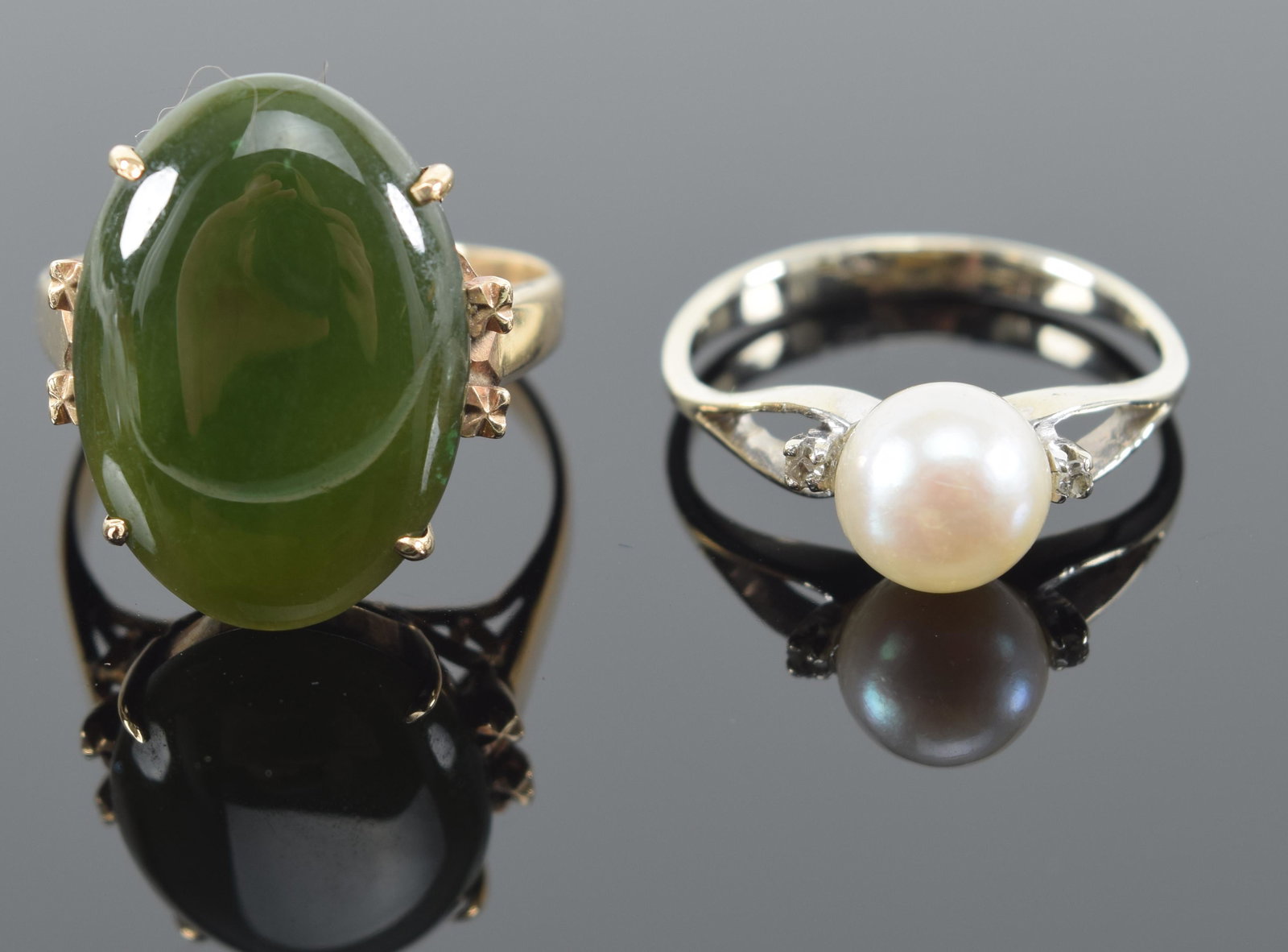 2 18K gold rings. 1) Oval jade type stone. Pierced design. Stone 0.75in length. Marked 18K. 2) Pearl: 2 18K gold rings. 1) Oval jade type stone. Pierced design. Stone 0.75in length. Marked 18K. 2) Pearl ring set in white gold. 2 tiny diamonds. Marked .750. 6.4 grams total weight.