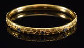 18K gold sapphire mounted bangle bracelet with raised wire work vine decoration. Oval hallmark.