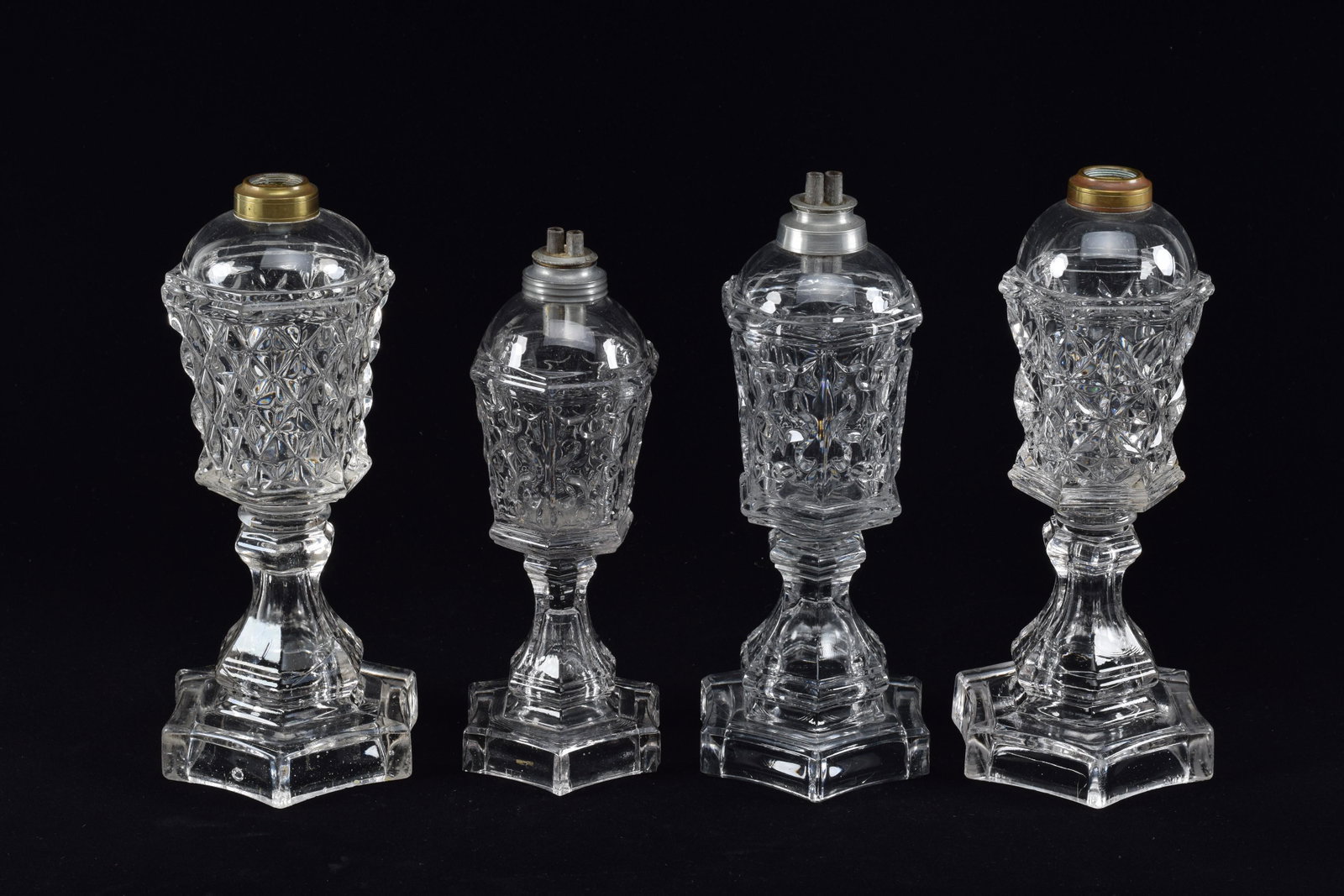 4 Flint glass whale oil lamps, mid 19th Century. Including a pair of Sandwich, no elements, star: 4 Flint glass whale oil lamps, mid 19th Century. Including a pair of Sandwich, no elements, star pattern and a pair of Armorial glass Hex base in two sizes. Pair height 10.75, others heights 11in & 10