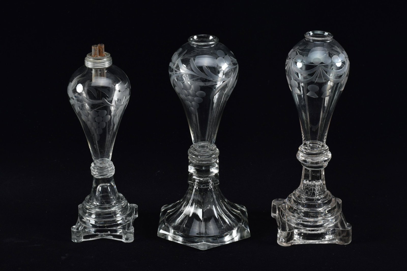 3 American glass whale oil lamps, mid 19th Century. Blown bulb-form fonts with grape vine cut: 3 American glass whale oil lamps, mid 19th Century. Blown bulb-form fonts with grape vine cut decoration. No burners. Tallest height 9in