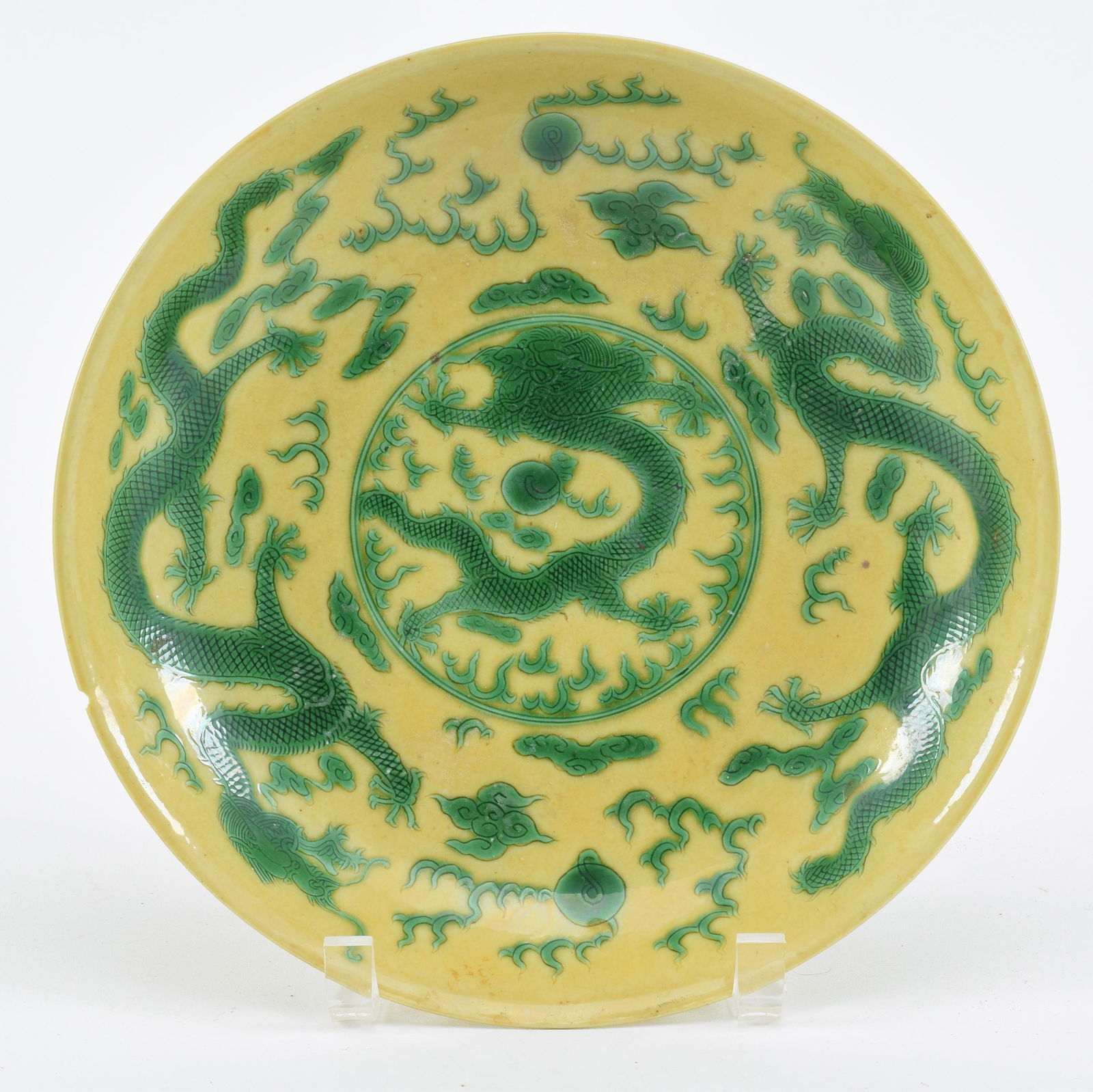 Porcelain bowl. China. Kang Hsi mark (1662-1722) and probably of the period. Yellow ground with: Porcelain bowl. China. Kang Hsi mark (1662-1722) and probably of the period. Yellow ground with green dragons. 9.5in diameter. Chip on rim.
