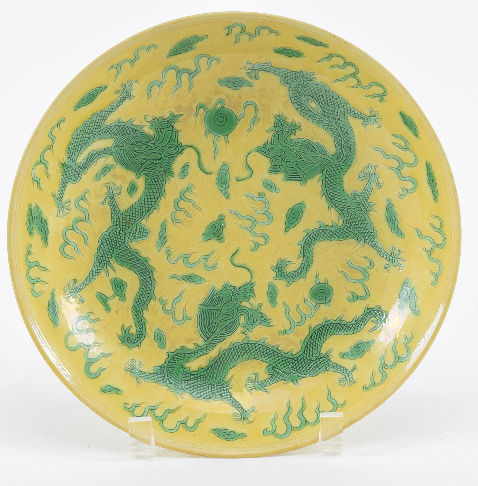 Porcelain bowl. China. Kang Hsi mark (1662-1722) and probably of the period. Yellow ground with: Porcelain bowl. China. Kang Hsi mark (1662-1722) and probably of the period. Yellow ground with green dragons. Small old chip on rim. Small tight hairlines on rim. 9.5in diameter.