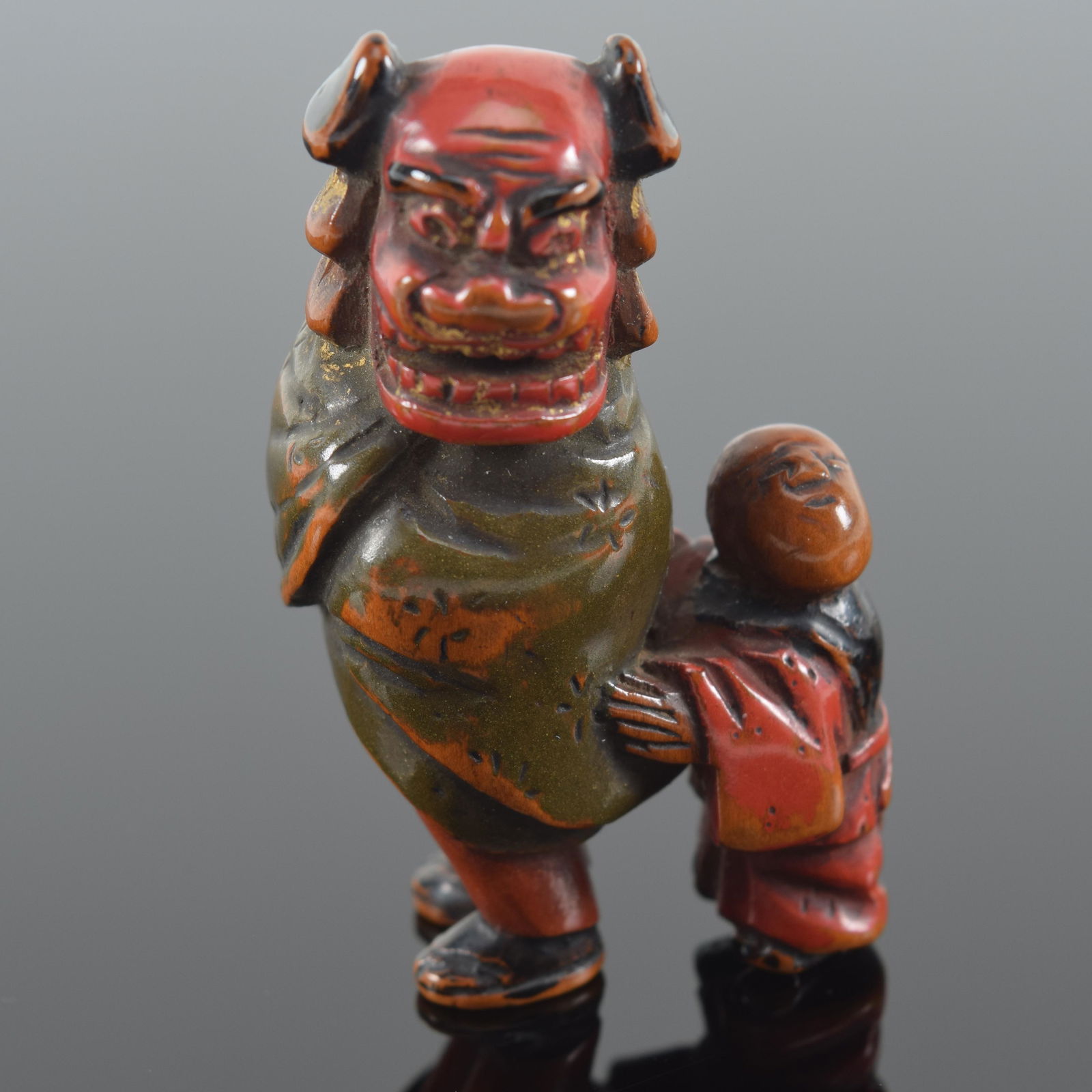 Netsuke. Japan. 19th century. 2 children playing with a lion dance mask and robe. 2in. Provenance: (1 of 5)
