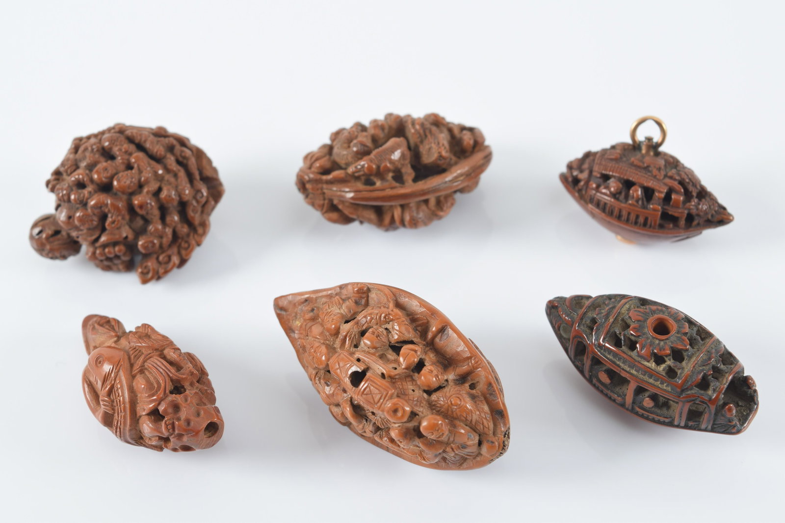 Lot of 6 finely carved peach pits. China. 19th century. Each about 1in length. Provenance: From the: Lot of 6 finely carved peach pits. China. 19th century. Each about 1in length. Provenance: From the collection of Donald Snow.
