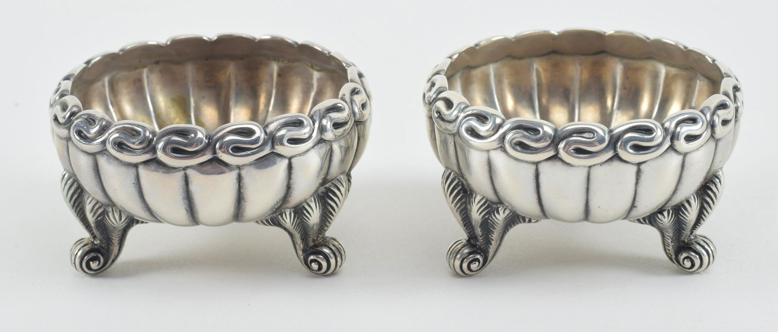 Pair of Tiffany & Co. sterling silver master salts, ca 1900. Scrolled foliate feet, ribbed bodies, (1 of 5)