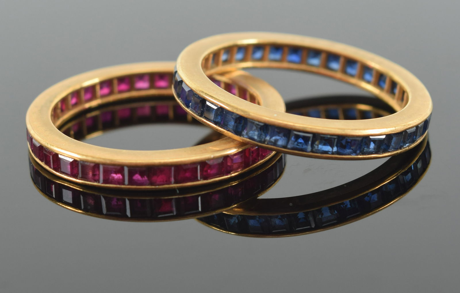 2 18K Gold eternity bands; one set with square-cut rubies, the other with square-cut sapphires, 6.01 (1 of 4)