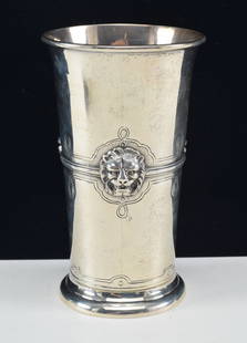 Large sterling silver beaker form cup. Decoration of lion's head masks set on a stipple ground band: Large sterling silver beaker form cup. Decoration of lion's head masks set on a stipple ground band around the middle of the cup. Partial maker's mark on side of cup. 7in high. 12.1 ozt.