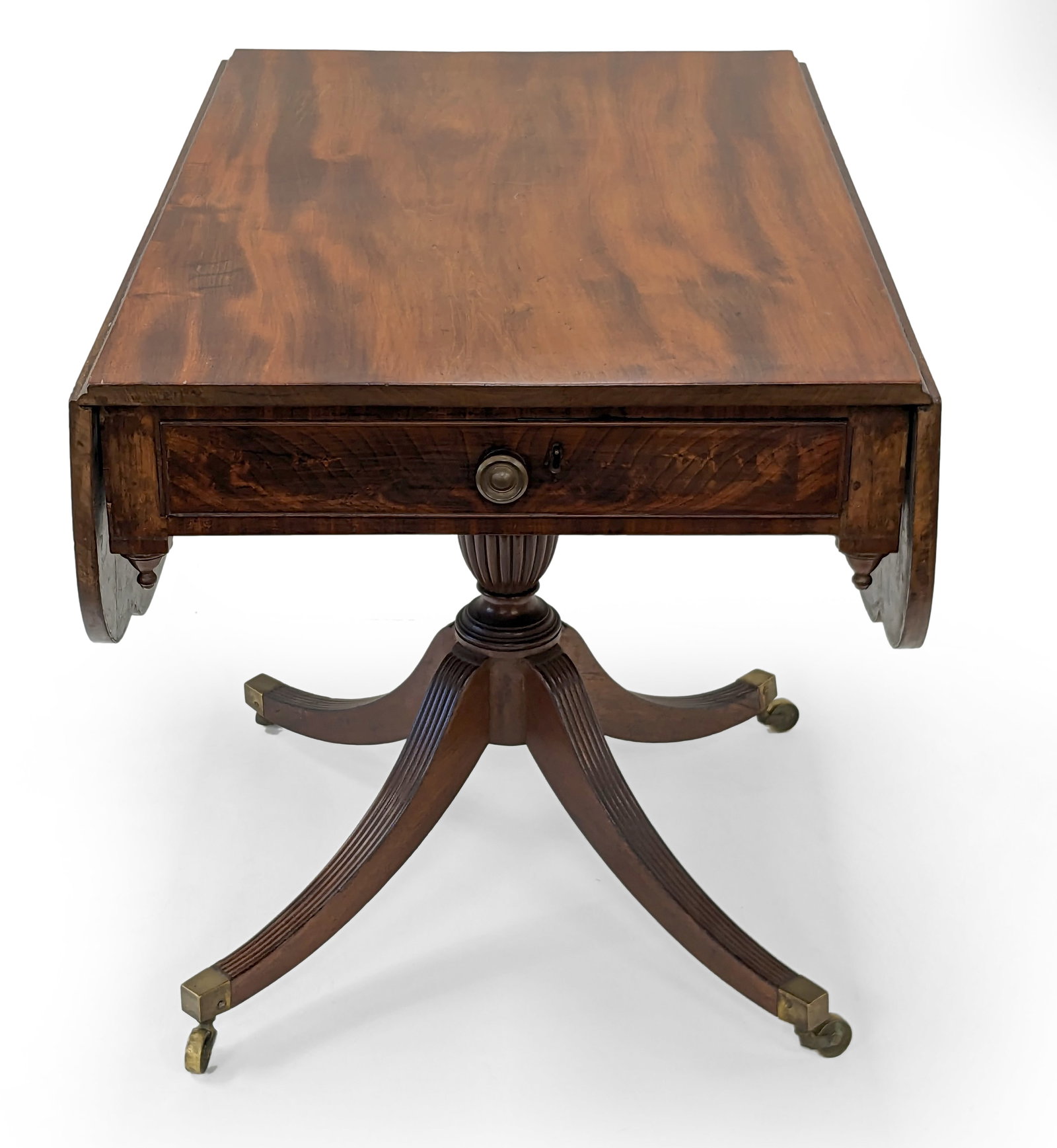 Federal mahogany drop leaf breakfast table, in the manner of Duncan Phyfe, New York circa 1810.: Federal mahogany drop leaf breakfast table, in the manner of Duncan Phyfe, New York circa 1810. Shaped drop leaves and single drawer in apron on a post with a reed urns joining four reed legs with bra