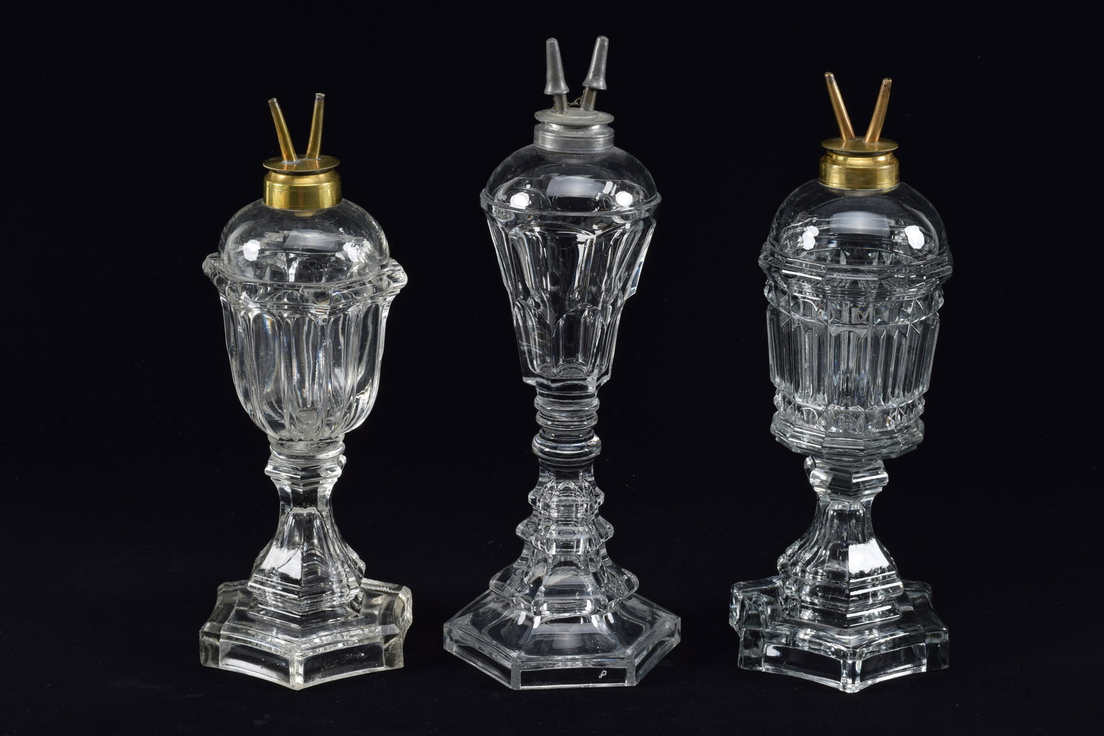 3 Sandwich glass lamps whale oil lamps, mid 19th Century. Faceted bodies, two with brass elements,: 3 Sandwich glass lamps whale oil lamps, mid 19th Century. Faceted bodies, two with brass elements, one pewter.
