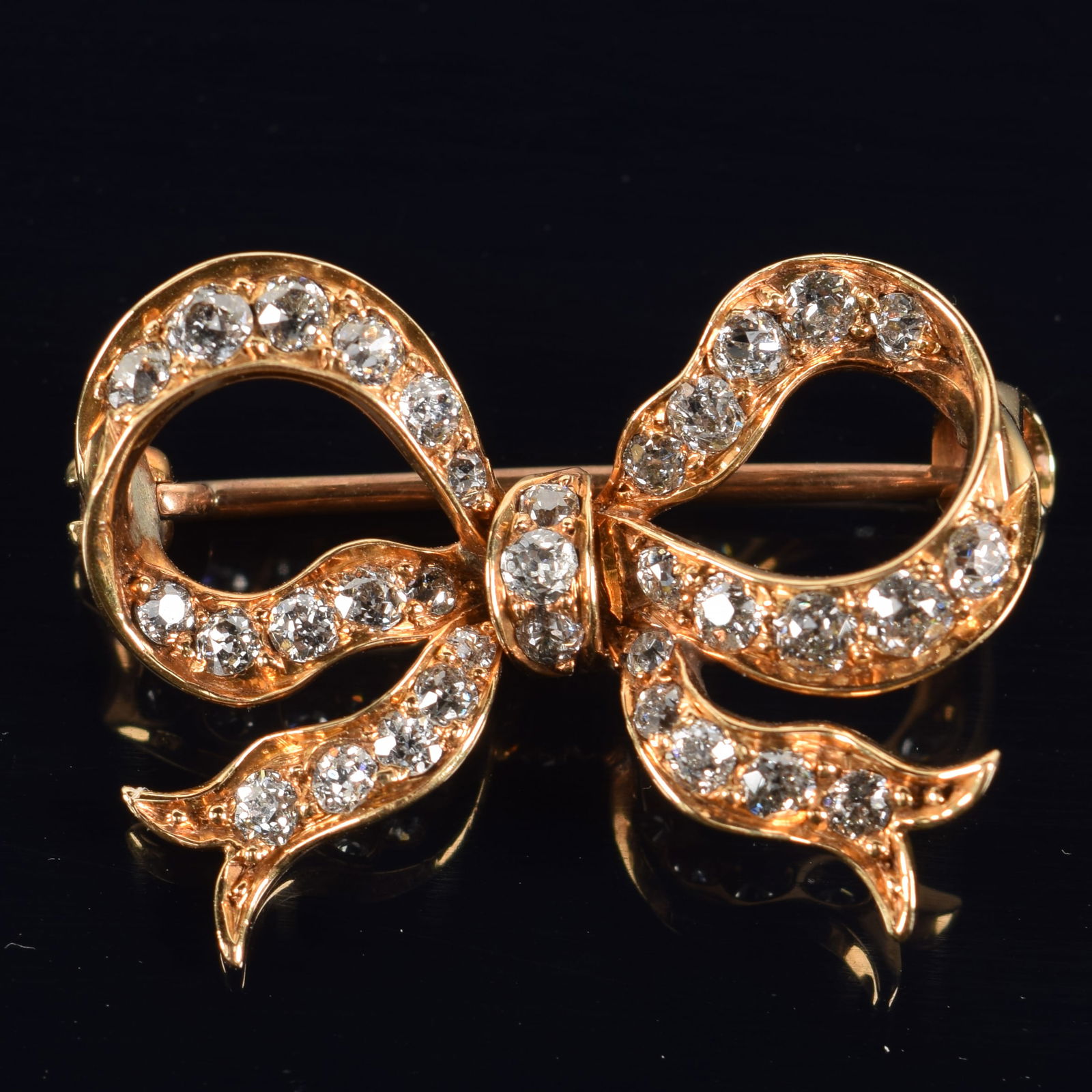 18K gold diamond mounted bow form pin. Marked 18K. 1in wide. 3.6 grams. (1 of 5)