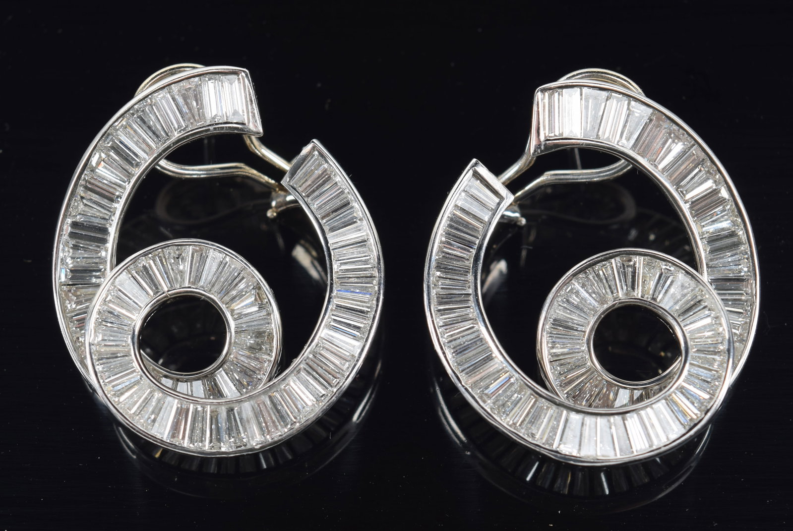 18K gold large 5.5CTW diamond mounted clip earrings. Snail form. Each with approx 64 graduated cut: 18K gold large 5.5CTW diamond mounted clip earrings. Snail form. Each with approx 64 graduated cut diamond baguettes. Measuring approx. 3.8 to 1.5mm to 2.8 to 1.2mm. Approx total diamond carat weight 