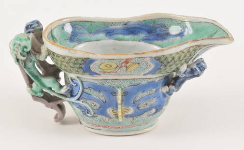 Porcelain wine cup. China. Kang Hsi period (1662-1722). Ritual archaic form Kuang with various: Porcelain wine cup. China. Kang Hsi period (1662-1722). Ritual archaic form Kuang with various appliqued chih lung. Famille verte enamel palette. Rim frits and glaze chips. Blue dragon on handle with