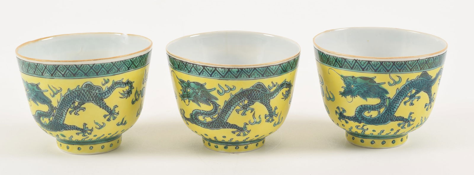 3 porcelain cups. China. Early 20th century. Yellow ground with aubergine dragons. 3.5 x 3in.: 3 porcelain cups. China. Early 20th century. Yellow ground with aubergine dragons. 3.5 x 3in. One with chip and crack.