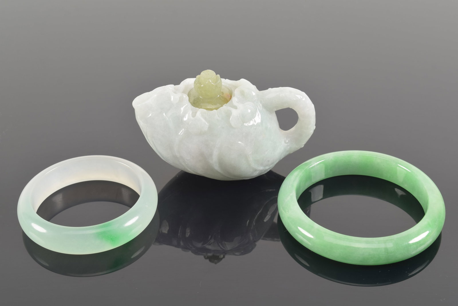 3 hardstone carvings. China. 20th century. A lavender jade wine pot and 2 bracelets. Ewer: 3.75in: 3 hardstone carvings. China. 20th century. A lavender jade wine pot and 2 bracelets. Ewer: 3.75in length.