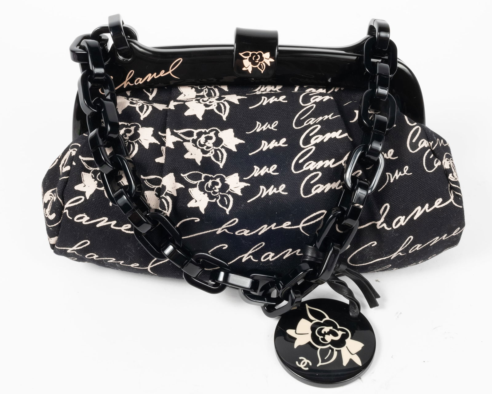 Chanel printed cloth small handbag with black lucite trim and lucite chain handle. Decorated lucite: Chanel printed cloth small handbag with black lucite trim and lucite chain handle. Decorated lucite clasp. In black with white lettering. Comes with Chanel Certificate of Authenticity card and product