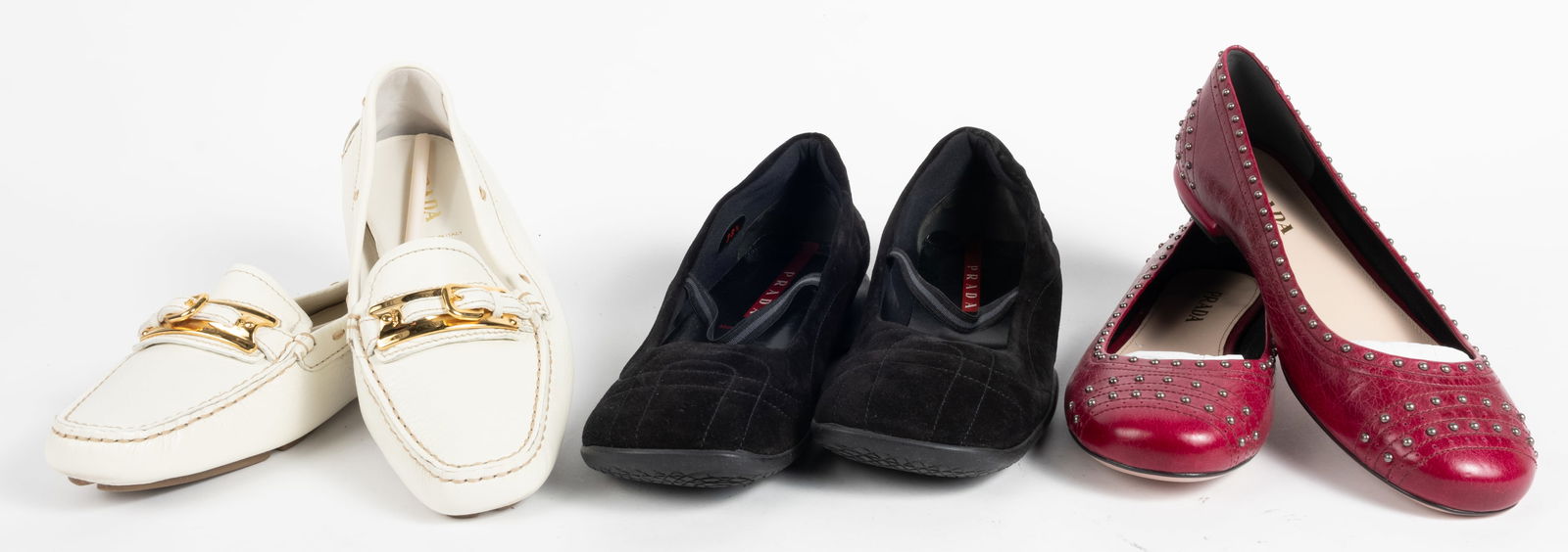 Three pairs of Prada shoes. (1) Prada flats with metal studs in burgundy. (size 38). (2) Leather: Three pairs of Prada shoes. (1) Prada flats with metal studs in burgundy. (size 38). (2) Leather loafers with gold buckle, cream color (size 38-1/2).(3) Black suede flats with elastic strap and stitch