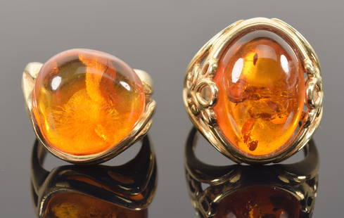 [2] 14K gold amber mounted rings. 1 oval form and 1 non-symmetrical round form. Each marked 14K.: [2] 14K gold amber mounted rings. 1 oval form and 1 non-symmetrical round form. Each marked 14K. Sizes 6.75 and 5. 11.3 grams total weight.
