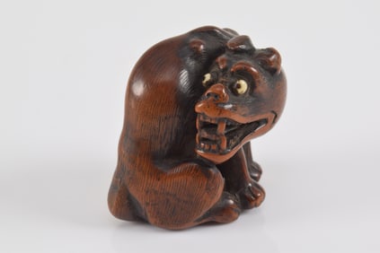 Carved wooden netsuke. Japan. 19th century. Seated turning ravening wolf with dramatic wide eyed exp