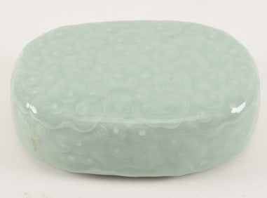 Porcelain hand warmer. China. 19th century. Surface carved with clouds beneath a celadon glaze.
