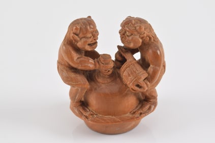 Carved wooden netsuke. Japan. 19th century. Masatomo. Two oni scouring a bell. 3.5 x 3.5cm.
