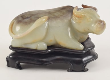 Jade bull. China. 19th/early 20th century. Fitted stand. Celadon stone with black markings. 7in