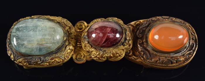 Belt buckle. China. 19th century. Gilt brass set with beryl, corundum, and opal. 3.25in length.