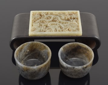 3 jades. A carved and pierced Yuan style rectangular plaque and a pair of grey jade wine cups.