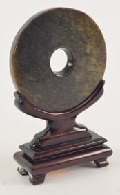 Jade pi. China. 19th century. Fitted stand. 5in diameter.