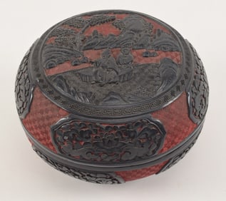 2 color cinnabar box. China. 19th century. Round form carved with landscape and flowers in black on