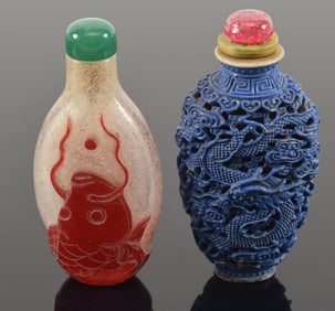2 snuff bottles. China. 19th century. One blue carved with dragons and clouds; the other red overlay