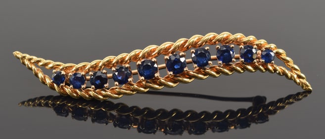 14K gold sapphire feather form pin. 10 channel set graduated sapphires. Largest about 3.6mm