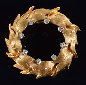 18K gold diamond wreath form pin. Overlapping foliate wreath design with 8 small round cut diamonds.