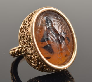 Ancient intaglio later mounted in 18K gold as a ring, in the style of Castellani. Carved amber or gl