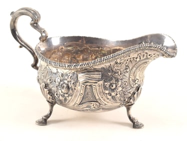 Georgian style sterling silver footed gravy boat, elaborate repousse decorated body on pad feet.