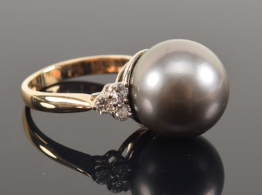 14K gold large pearl solitaire ring. Pearl measures approx. 13.5mm diameter. Flanked by 3 round cut