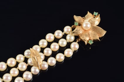 Pearl bracelet with 14K gold emerald mounted floral clasp. Triple strand bracelet with gold foliate