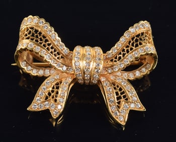 18K gold diamond mounted ribbon form pin. Perimeters with bands of tiny round diamonds and openwork