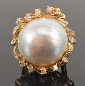 18K gold mabe pearl and diamond mounted ring. Pearl about 18mm diameter. Surrounded by small round