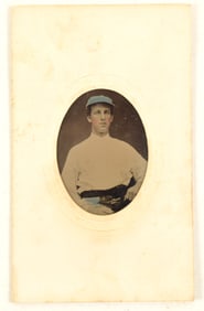 19th century tintype of seated baseball player in uniform with blue tinted hat. On Baird's,