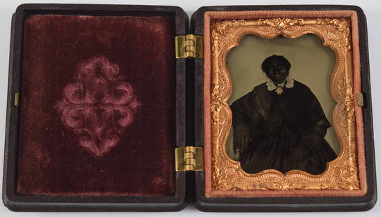 19th century tintype of an African American woman seated wearing a black dress and white lace: 19th century tintype of an African American woman seated wearing a black dress and white lace bonnet. Gilt accented brooch. Image: 2.5 x 2in. Case: 3 x 2.5in.