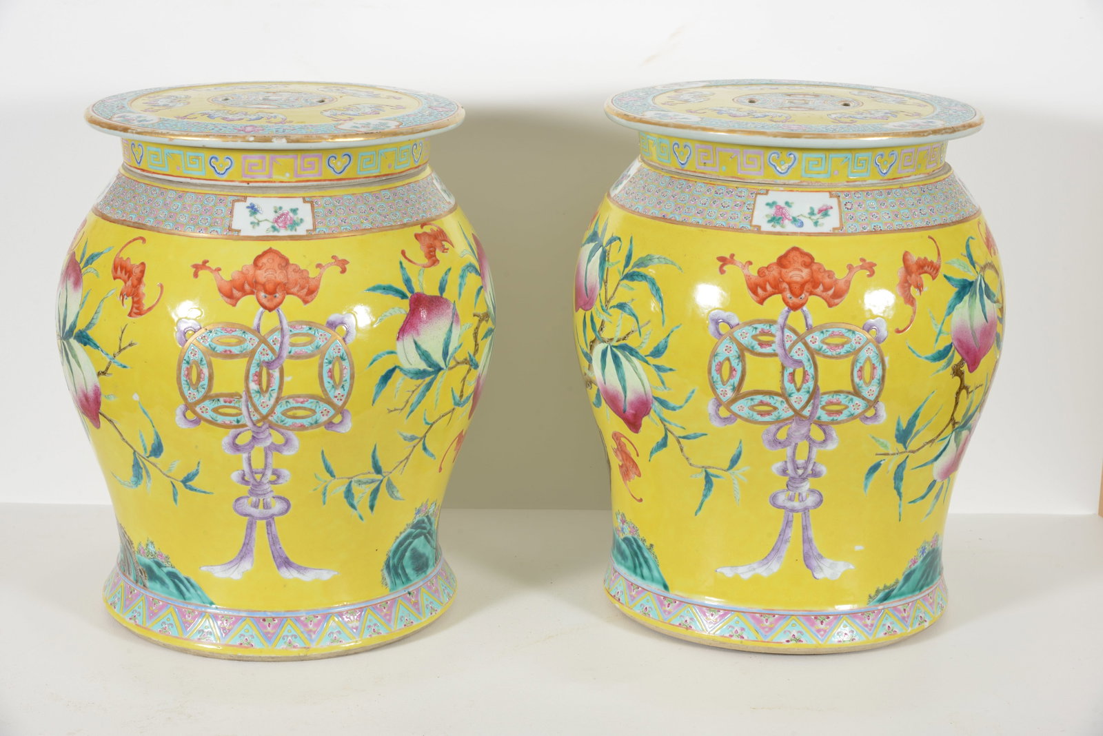Pair of vasiform garden seats. China. Mid 19th century. Decoration of peaches, bats, and cash coins: Pair of vasiform garden seats. China. Mid 19th century. Decoration of peaches, bats, and cash coins on a yellow ground. Geometric floral borders. Several scattered glaze chips and light scratches to y