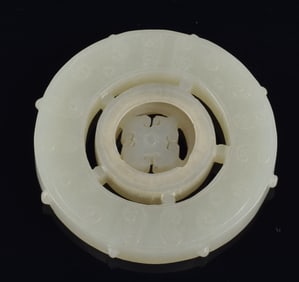 Jade disc pendant. China. 19th/20th century. Pierced and carved comma decoration. Central disc