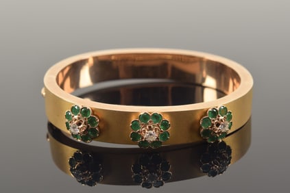 14K gold diamond and emerald bangle bracelet. 3 flower form settings with raised central diamond