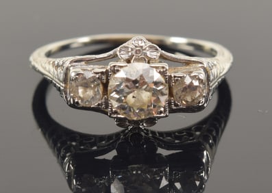Antique 18K white gold diamond ring. Central round cut diamond (5.1mm) flanked by two smaller round