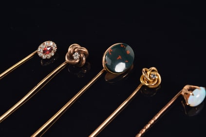 Lot of 5 gold stick pins. 1) 10K spiral head pin set with light blue stone. 2) [4] 14K pins with